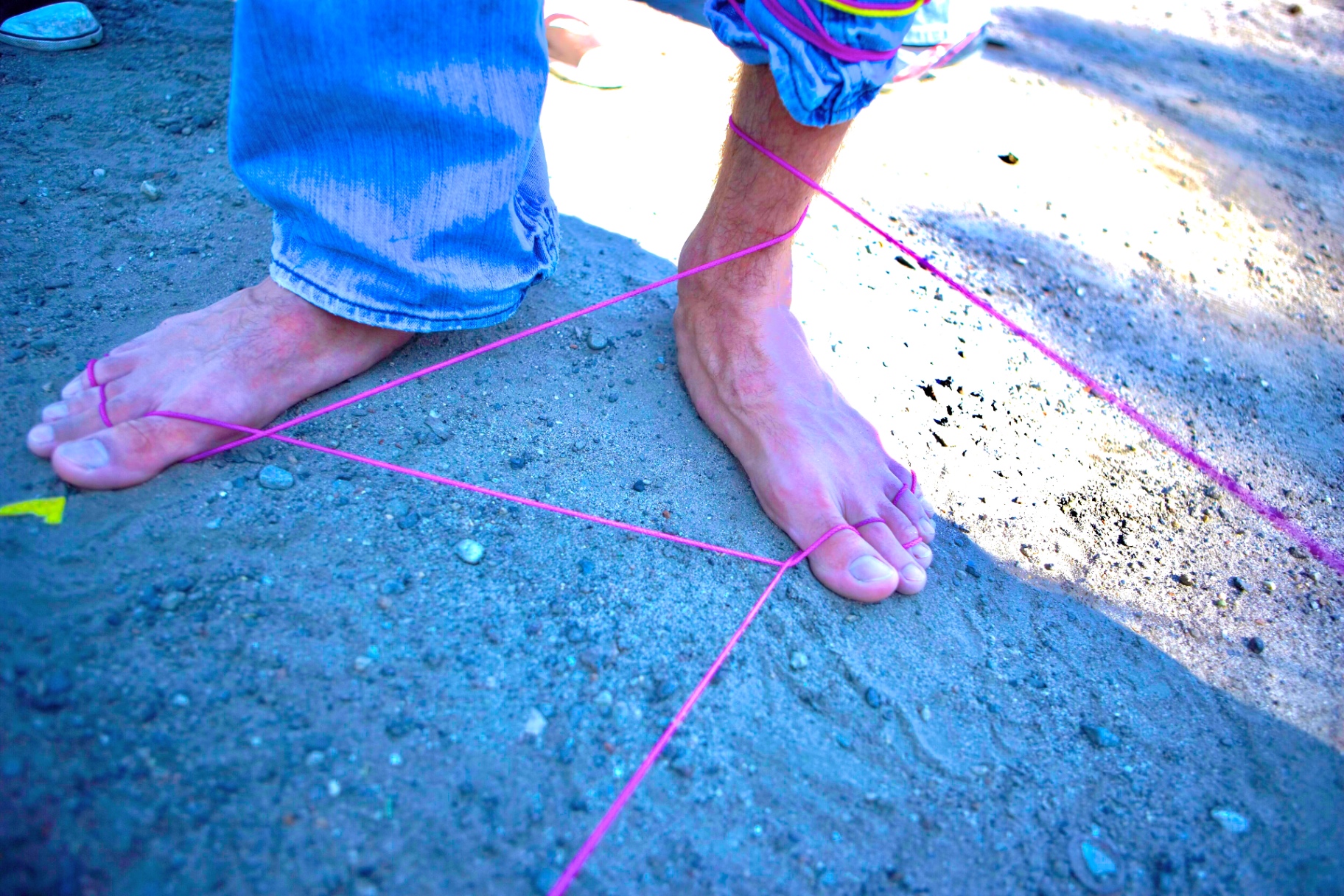 Bare feet entangled in pink string on the grass
