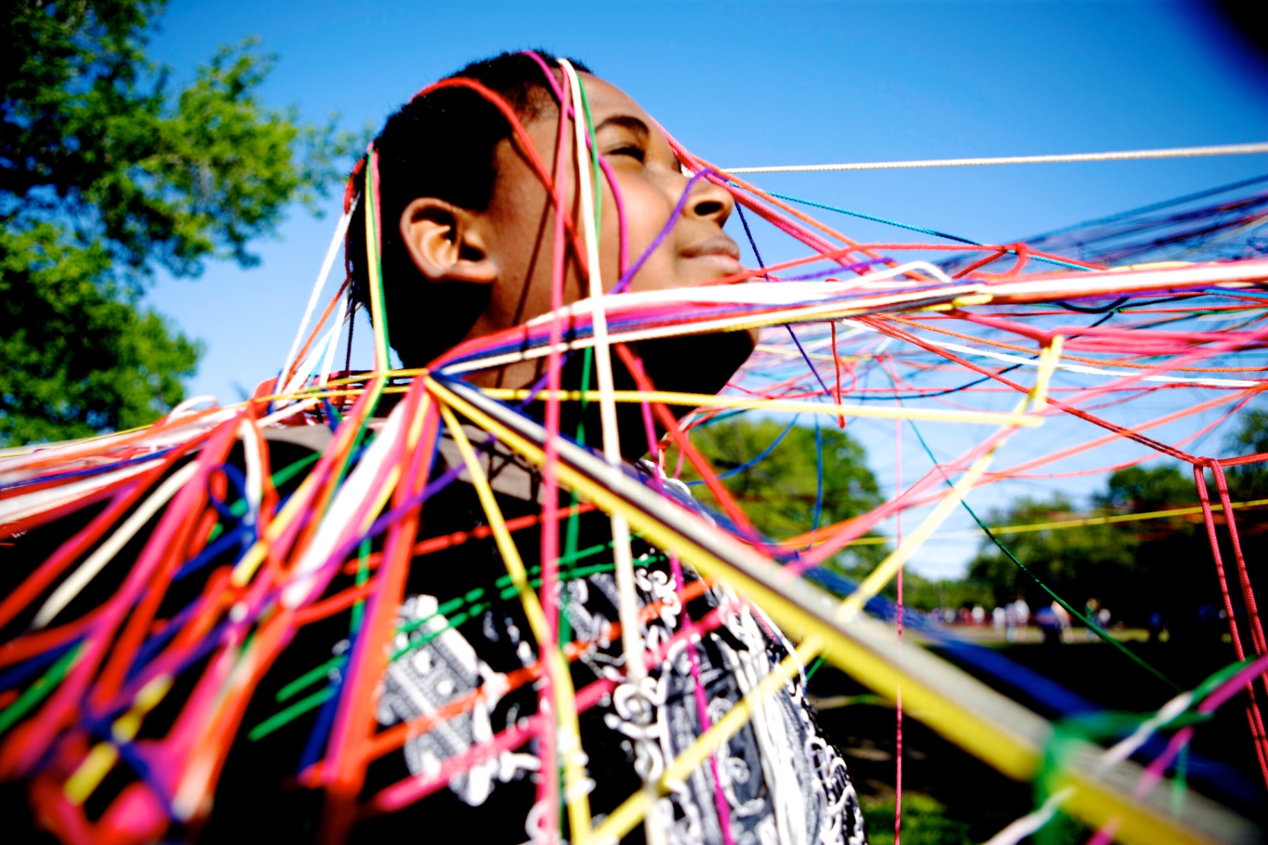 Child with head and neck wrapped in glowing rainbow elastic strings